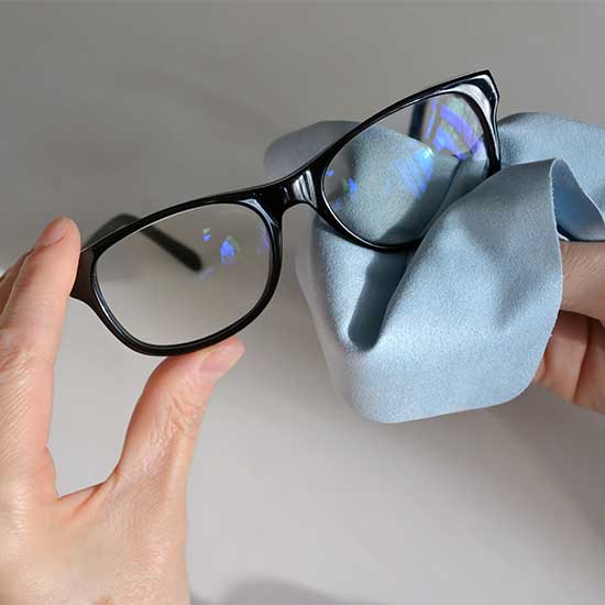 Brille wird mit einem Mikrofasertuch gereinigt